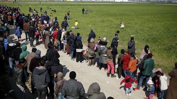 Migrants and refugees queue to receive food at a makeshift camp at the Greek-Macedonian border near the village of Idomeni