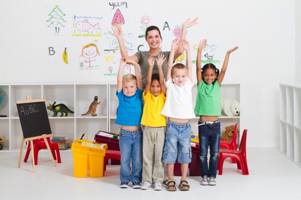 cheerful teacher and preschool kids in classroom
