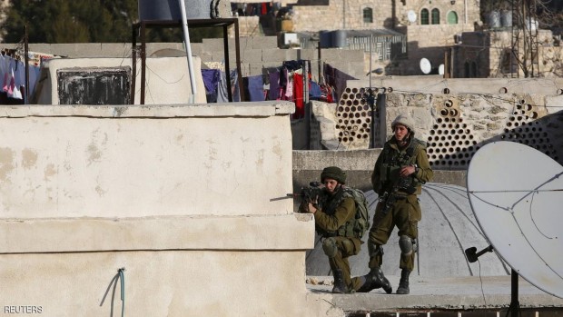 جندي إسرائيلي يصوب بندقيته صوب فلسطينيين في الخليل