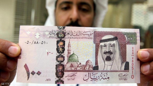 موظف بنكي يستعرض ورقة نقدية فئة 100 ريال سعودي في الرياض - أرشيف