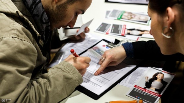 لاجئ يعبئ طلبا للعمل في معرض للوظائف في برلين