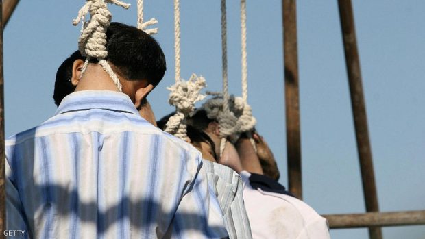 Five people hang limply from the nooses