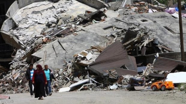 Residents walk past buildings which were damaged during security operations and clashes between Turkish security forces and Kurdish militants, in Yuksekova in the southeastern Hakkari province